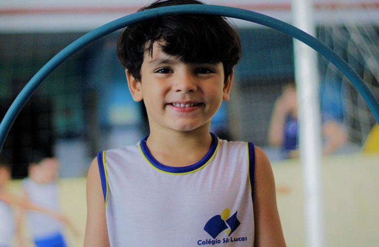 Menino sorrindo segurando um bambole no colegio são lucas